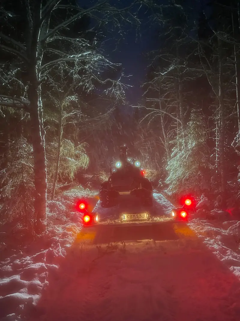 Terrängmaskin och släp på en snötäckt skogsväg